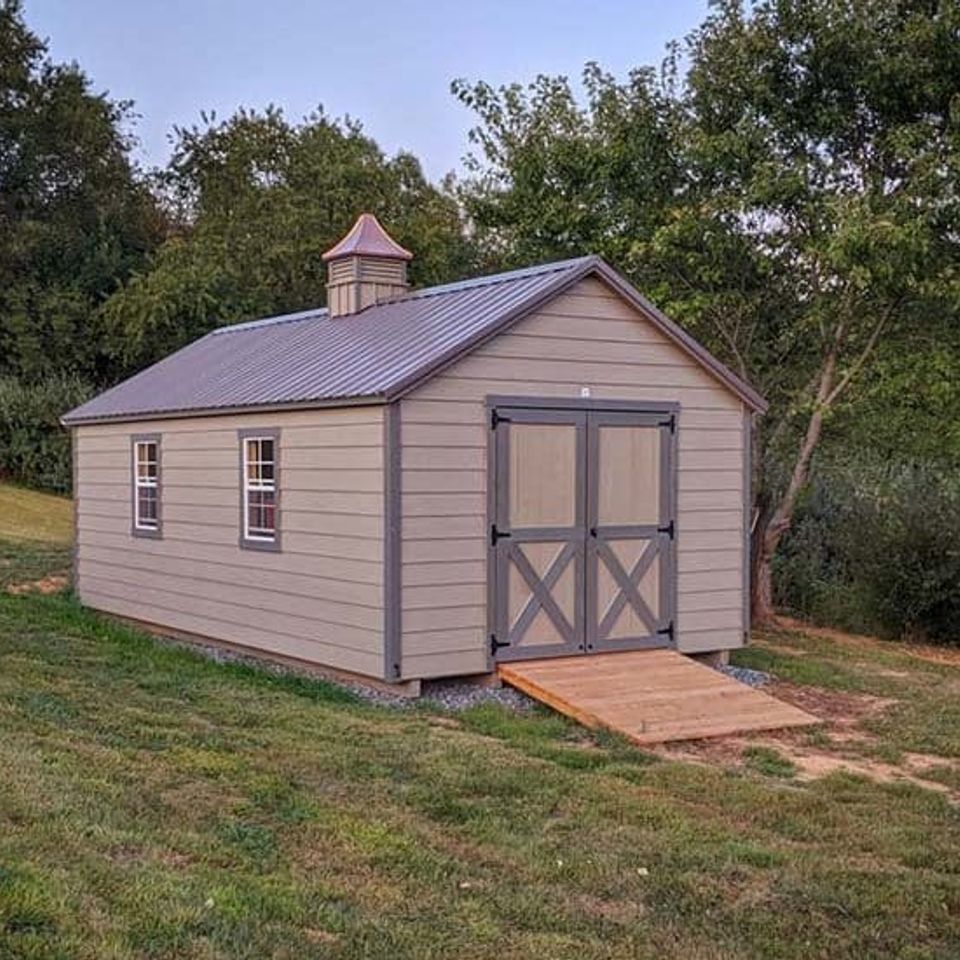 Tan cottage shed with cupola, double doors and wood ramp installed on a Knoxville TN lawn