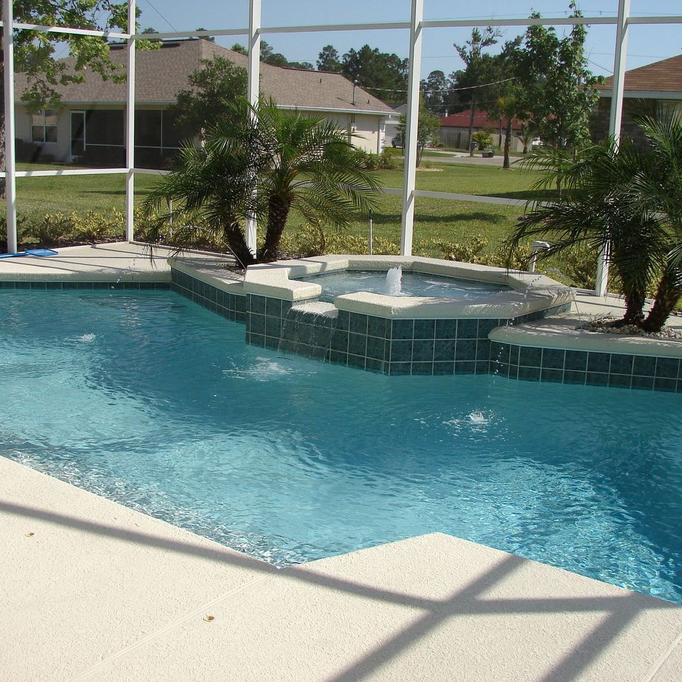 Custom backyard pool deck featuring an inlaid spa with decorative tile accents and a seamless cement patio surround by Roseville Concrete Solutions.