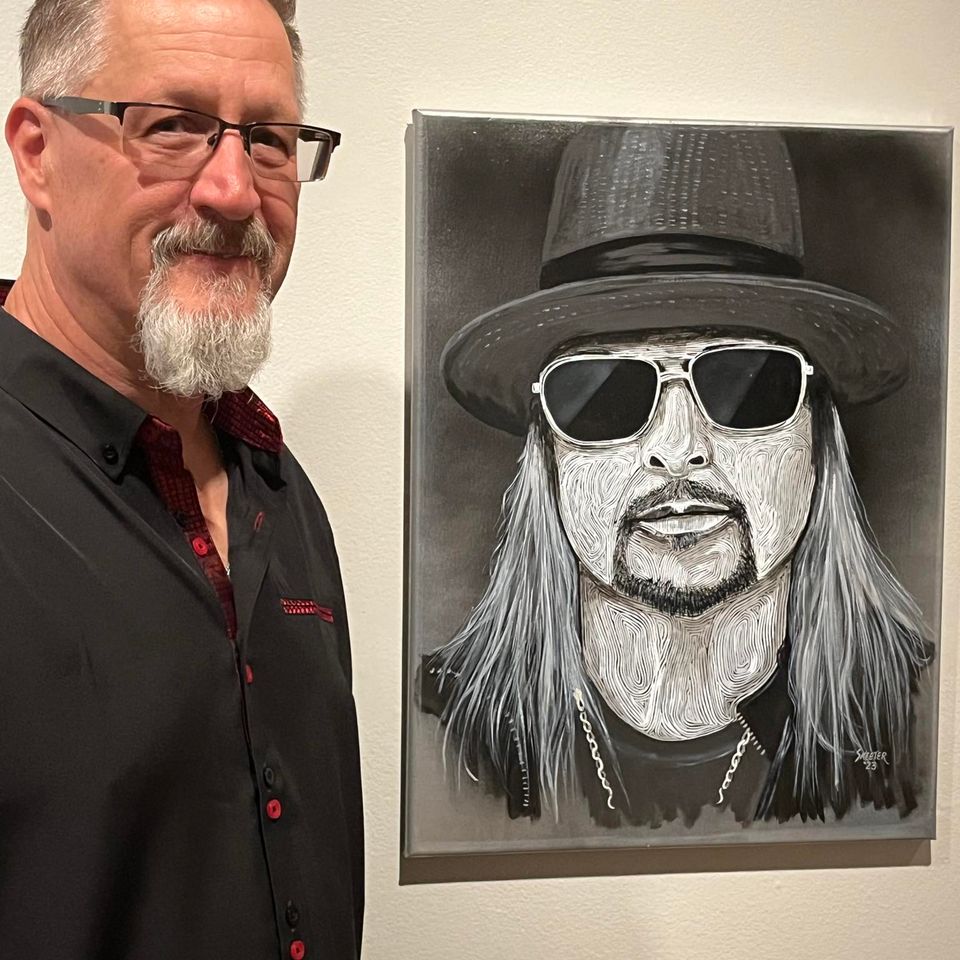 Artist Keith “Skeeter” Sturgeon standing beside his black-and-white custom portrait painting.