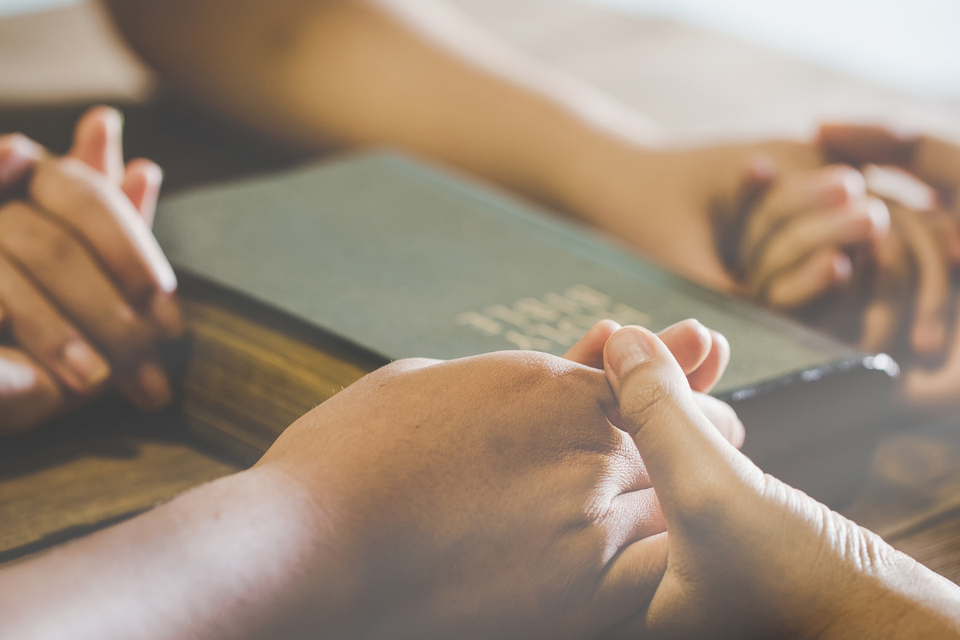 Church members holding hands in prayer during a gathering at Grace Evangelistic Temple Church.
