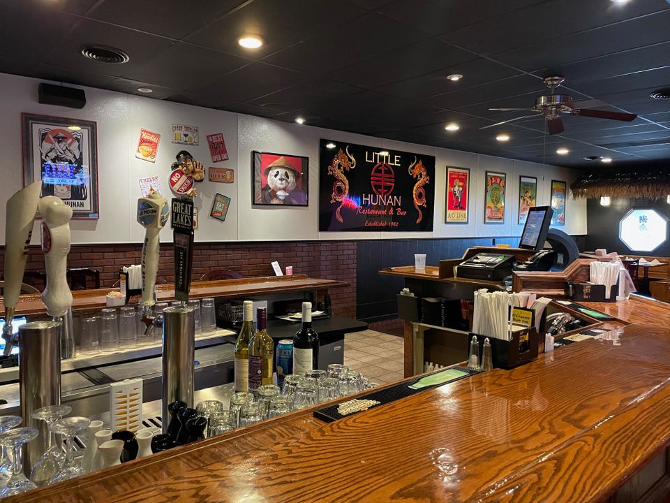 Interior view of Little Hunan Restaurant featuring the bar area, seating, and welcoming dining environment.