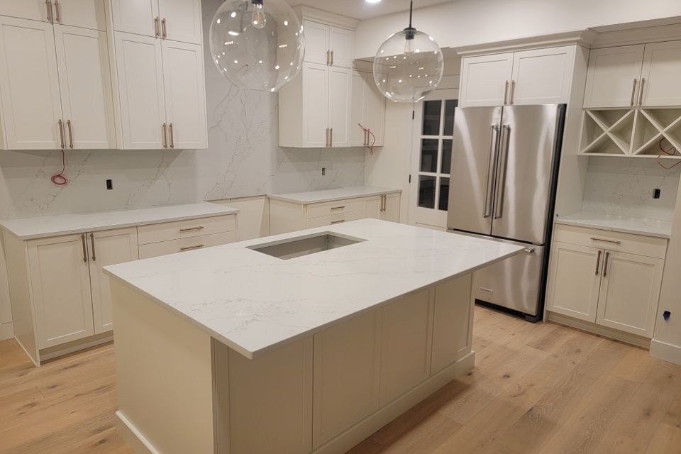 White countertop matching cupboards and stylish round light and metallic refrigerator