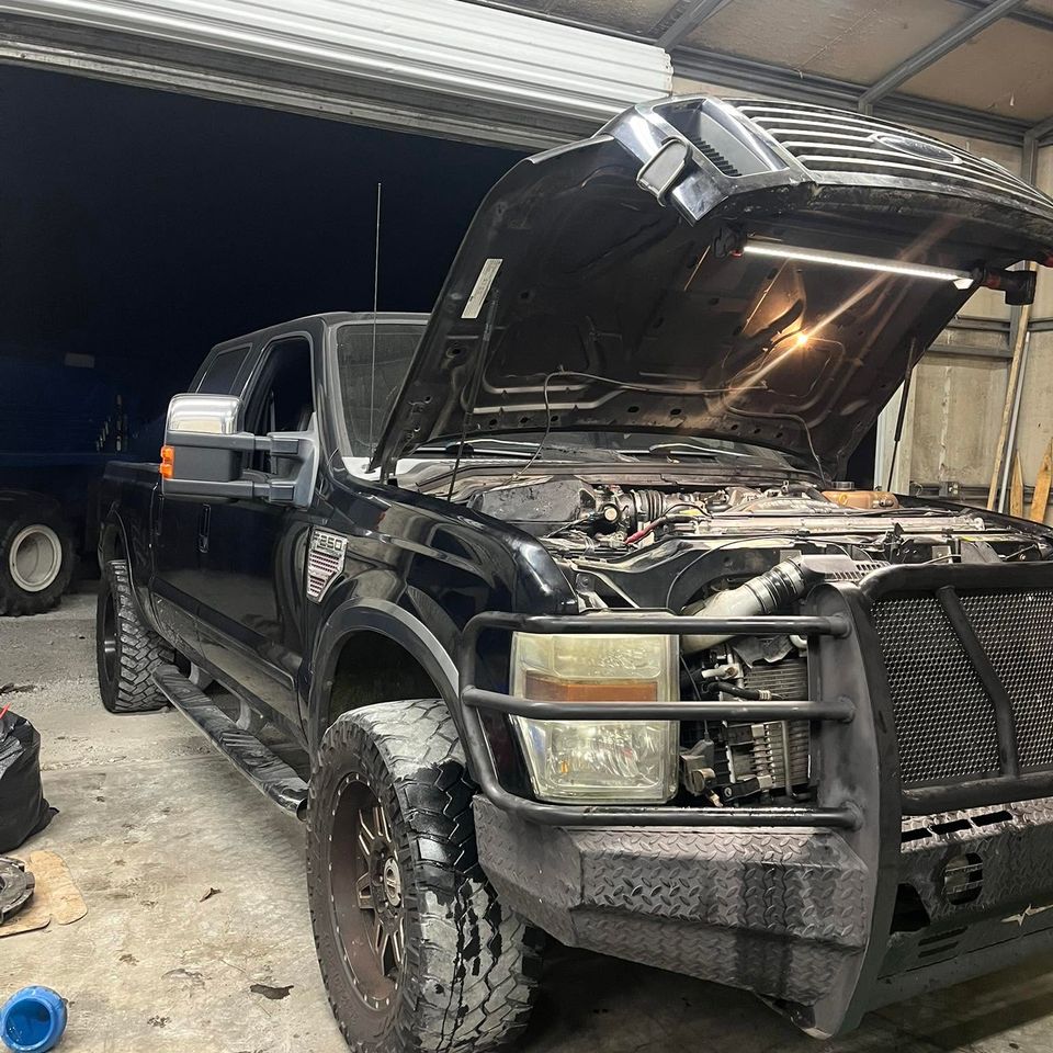 Black Ford F-250 diesel truck with hood open inside repair shop service bay in Arab Alabama