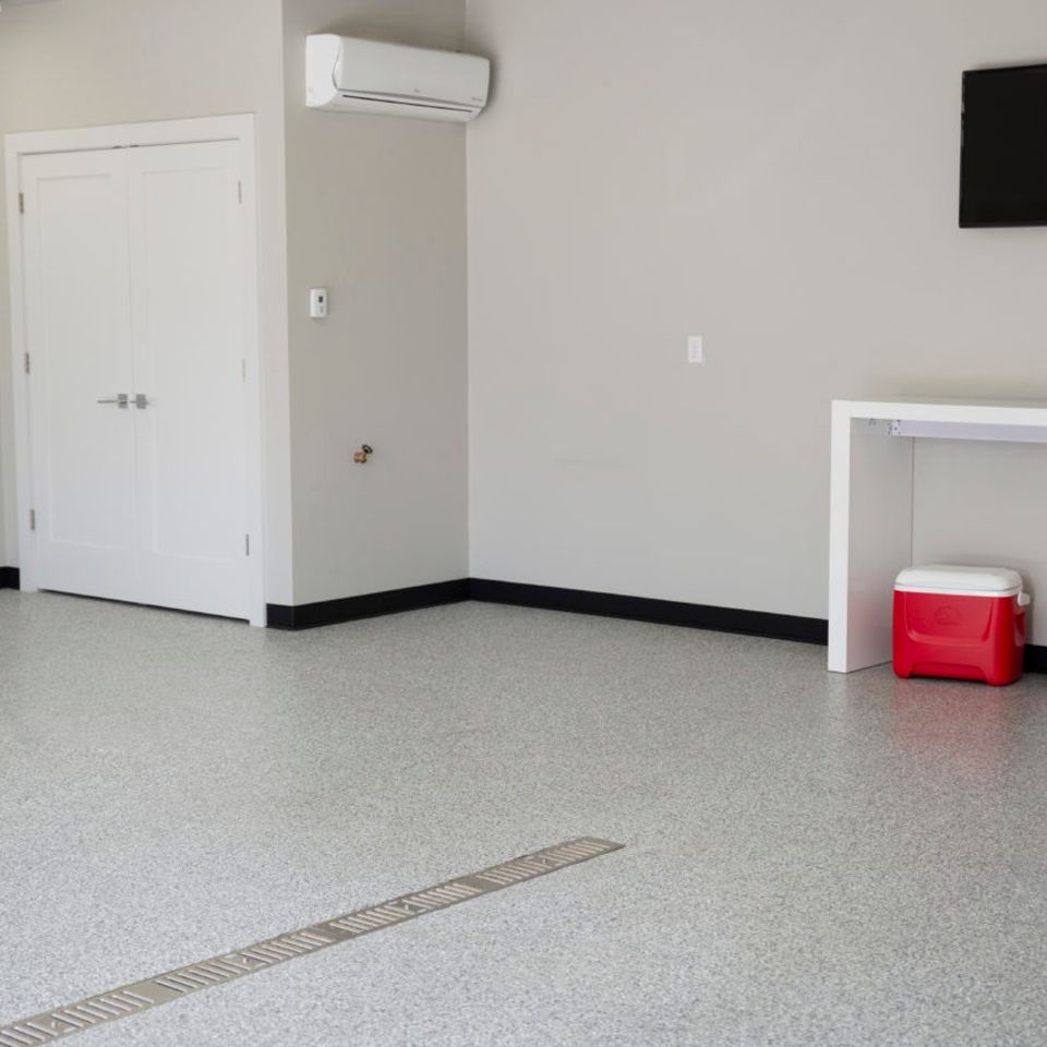 Clean garage with light gray EverStone Flakes flooring and a floor drain.