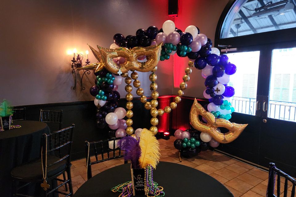 Balloon arch with oversized Mardi Gras Beads and Mardi Gras Masks at a corporate event.