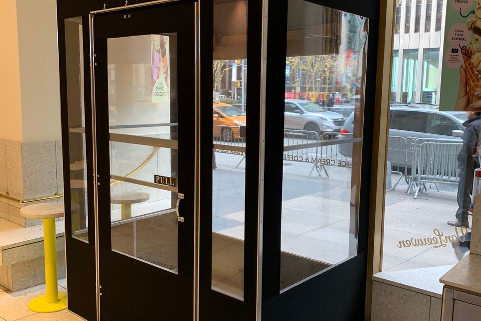 Black framed seasonal vestibule with clear vinyl panels inside a Midtown Manhattan storefront entrance