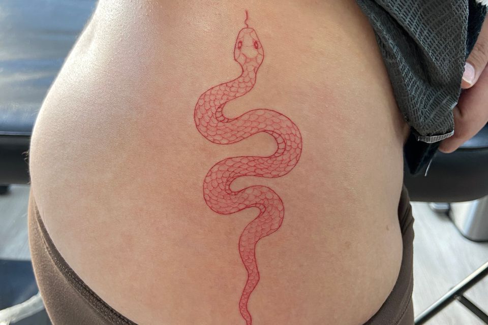Image of a red crawling snake on a womans right side