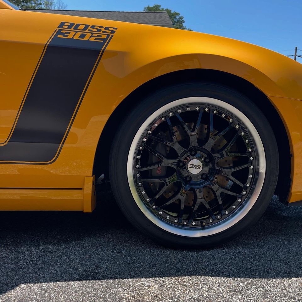 Close-up of a polished black SVE wheel and Boss 302 fender stripe after exterior cleaning