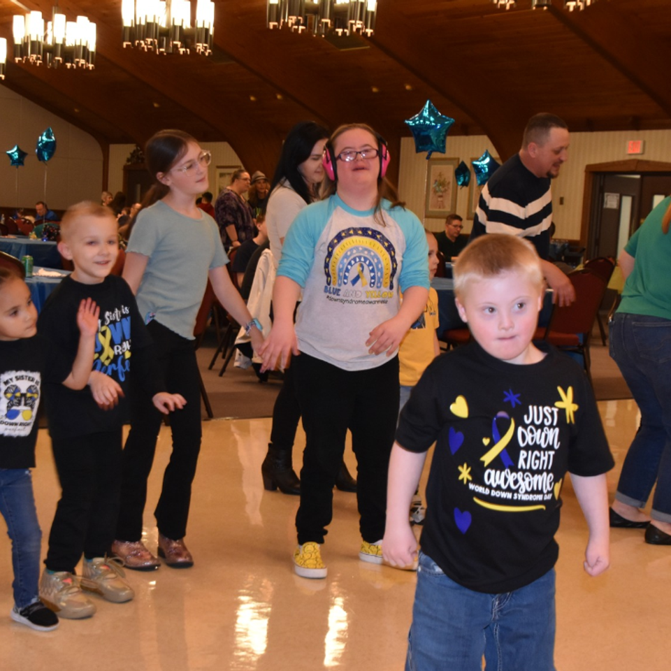 Children and participants dancing together during a Down Syndrome Association of the Valley community celebration.
