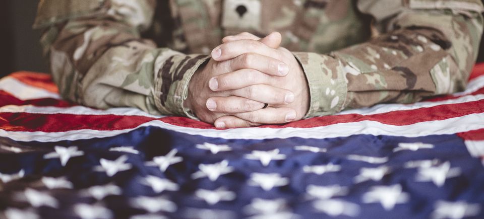 American soldier mourning praying with american flag front him