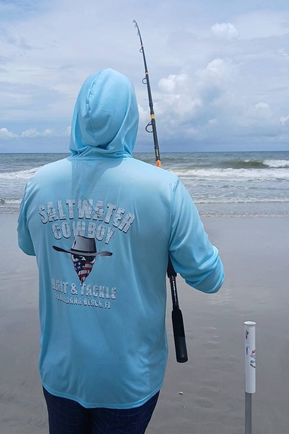Man fishing on the beach wearing a Saltwater Cowboy sweatshirt