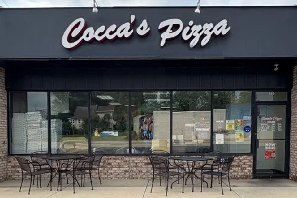 Cocca’s Pizza Girard, Ohio storefront featuring a black façade, large front windows, outdoor patio seating, and a white Cocca’s Pizza sign above the entrance.