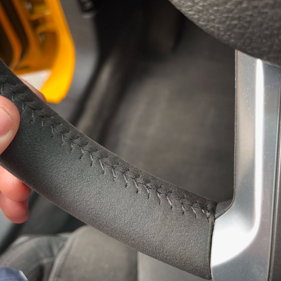 Close-up of a cleaned suede steering wheel with gray stitching after interior detailing