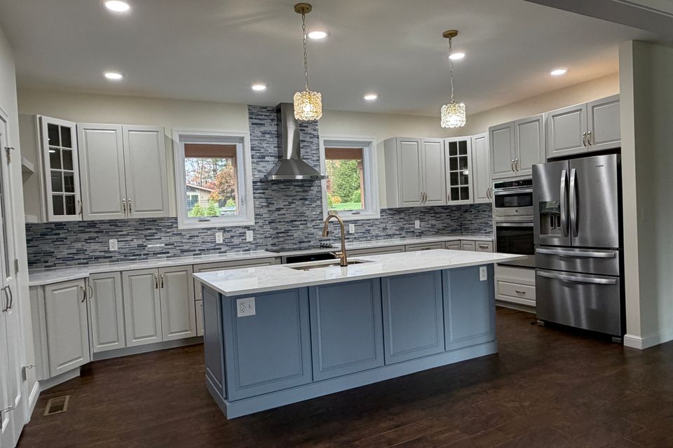Custom kitchen completed by Manning Construction Co., Inc. featuring custom cabinet, a large center island, quartz countertops, stainless steel appliances, and a tile backsplash.