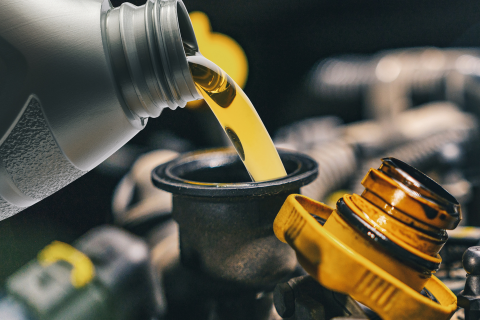 Engine oil being poured into a vehicle during a professional oil change service.