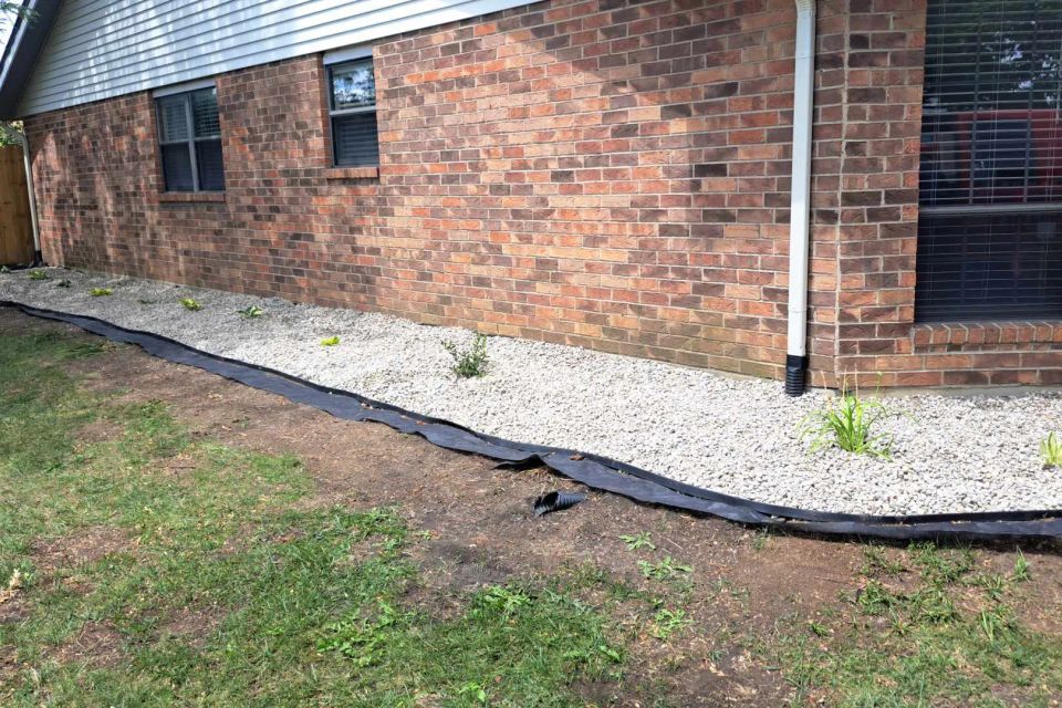 White gravel installed along a home's foundation to improve drainage and create a clean landscape border.