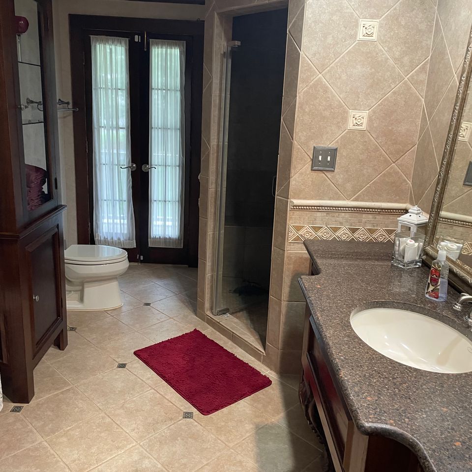 Clean tiled bathroom with polished vanity and glass shower after a house cleaning service in Virginia Beach VA