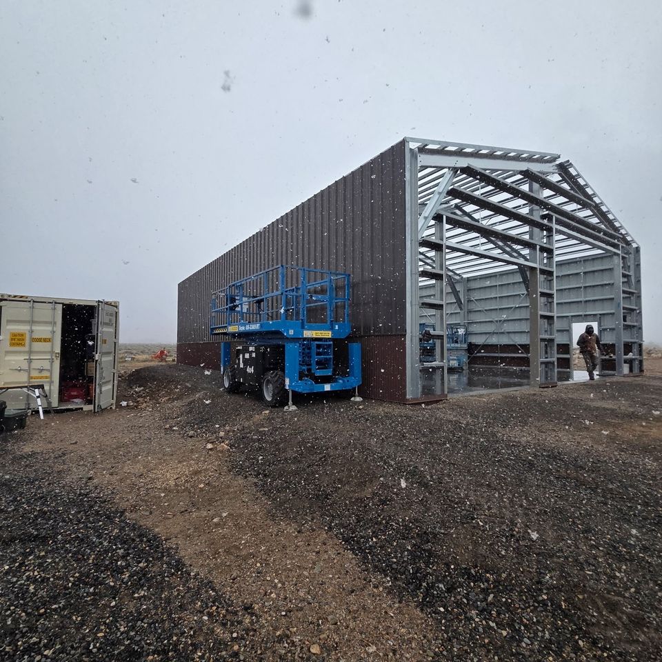 Metal building framing and wall panels going up with scissor lift on site in Trout Creek Montana