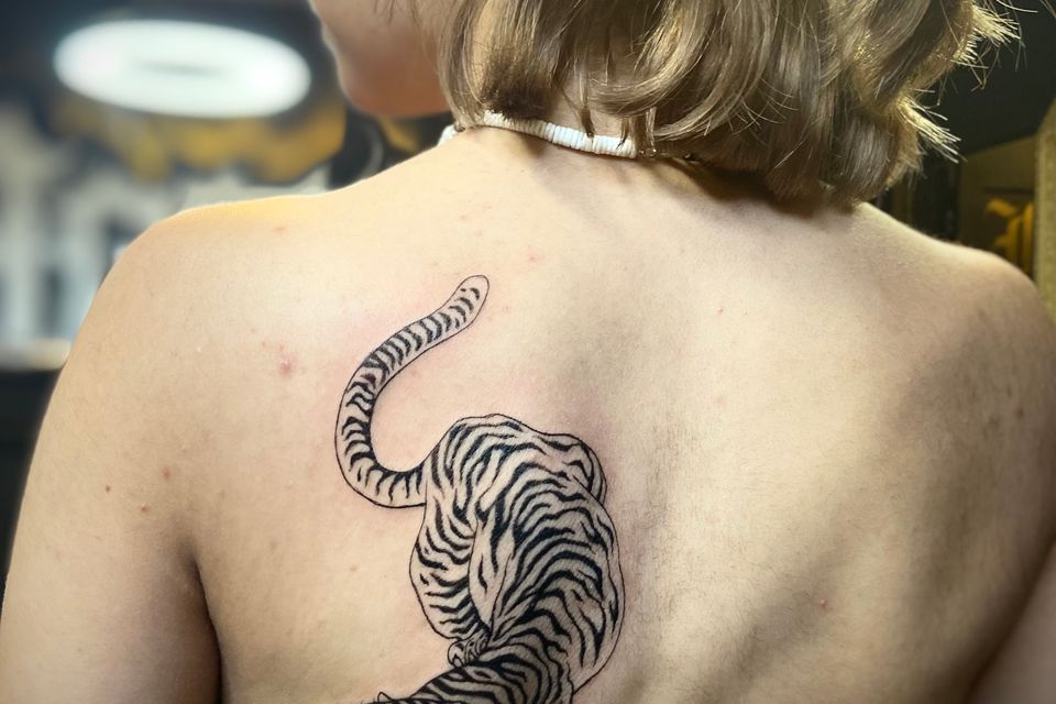 Image of a tiger tattoo on the back of a woman in black & grey