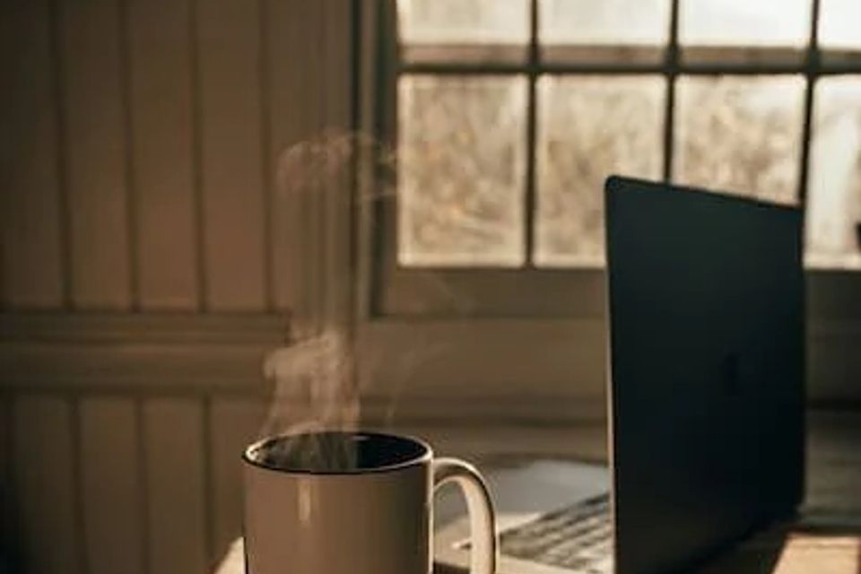 Steaming cup of coffee by laptop 