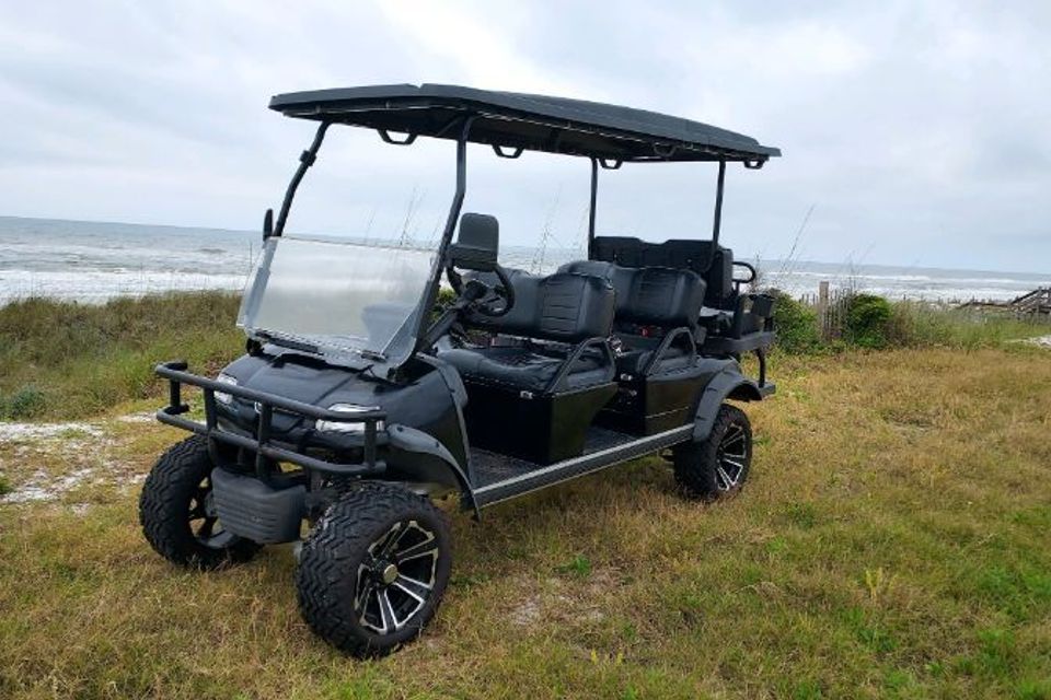 Black lifted six-passenger golf cart rental parked on the grass beside the beach in Destin