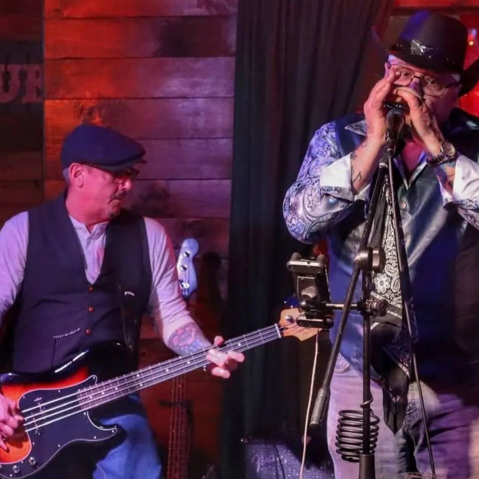Roadside bassist and harmonica player performing together during a live blues set at a Long Island pub