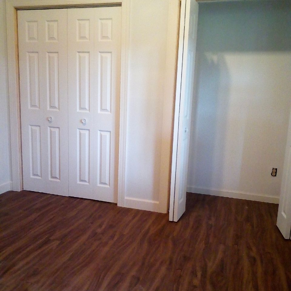 Bedroom closet with white bifold doors and dark laminate flooring installed in Chagrin Falls Ohio