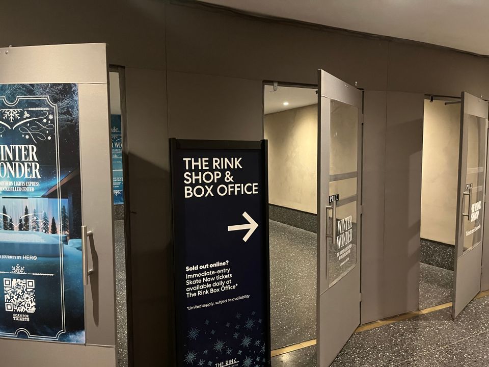 Brushed aluminum vestibule with a glazed door built inside a retail store entrance, photographed from the sales floor