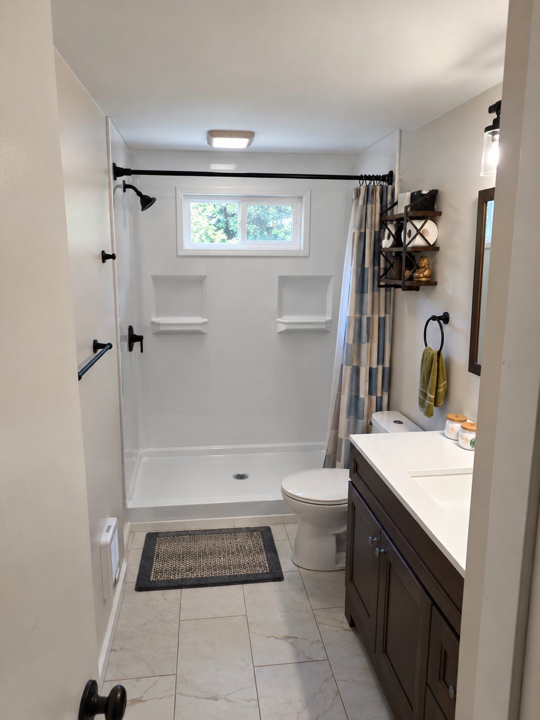 White grout-free walk-in shower that replaced an old bathtub, with built-in shelves and a window, installed by 1st Addition Remodeling