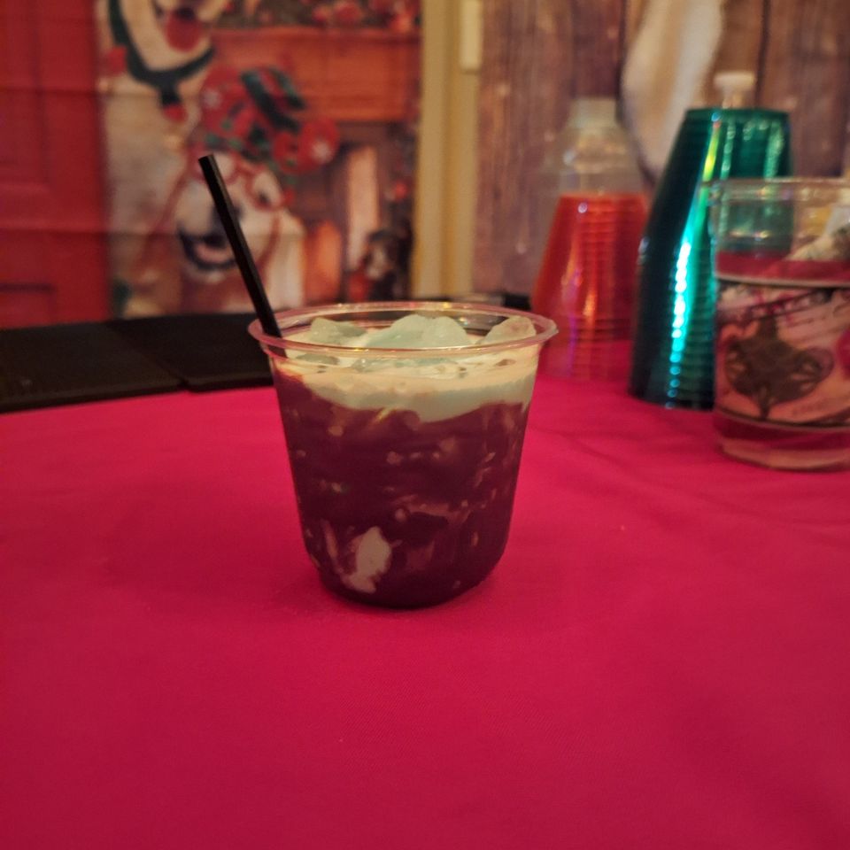 Cocktail in a cup with ice on a red table at a holiday party