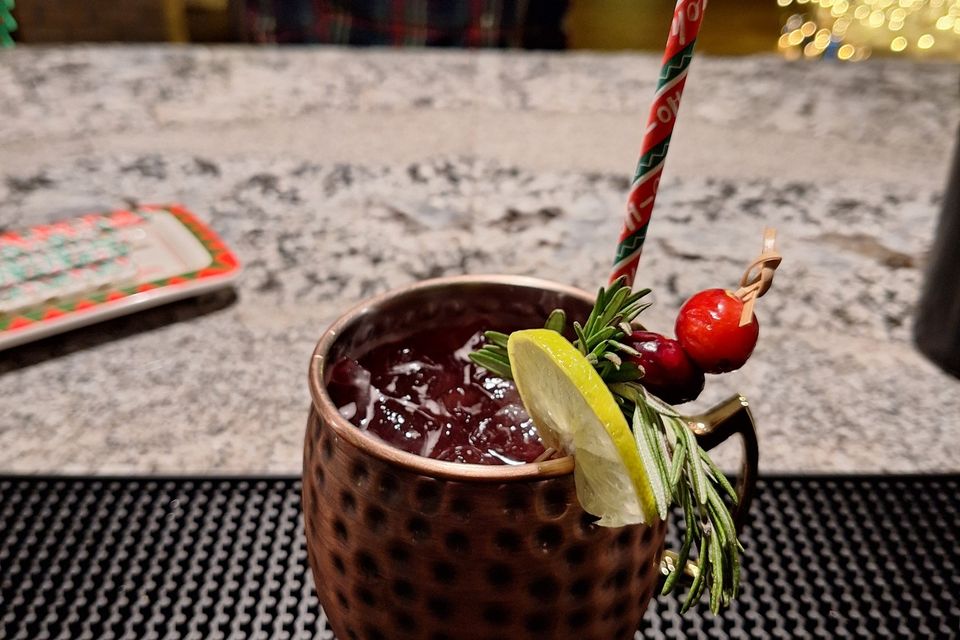 Berry and Bright Mule with lime, rosemary, and cranberry garnish on a bar counter