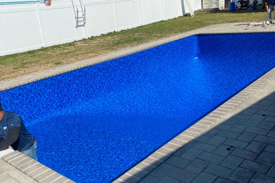 New blue vinyl liner installed in a rectangular inground pool with paver patio on Long Island