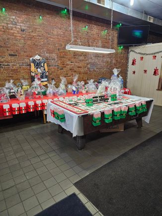 Tables decorated with raffle baskets, prizes, and holiday-themed decorations at an indoor event venue.