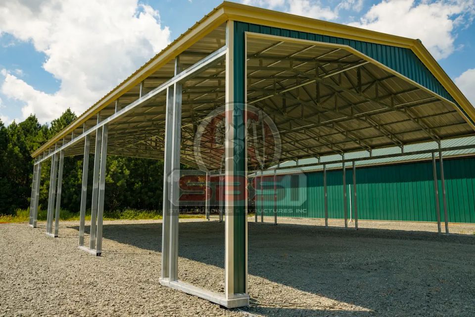 Green and yellow steel carport with open framing on gravel lot with SBSI watermark representing steel carports in Alabama