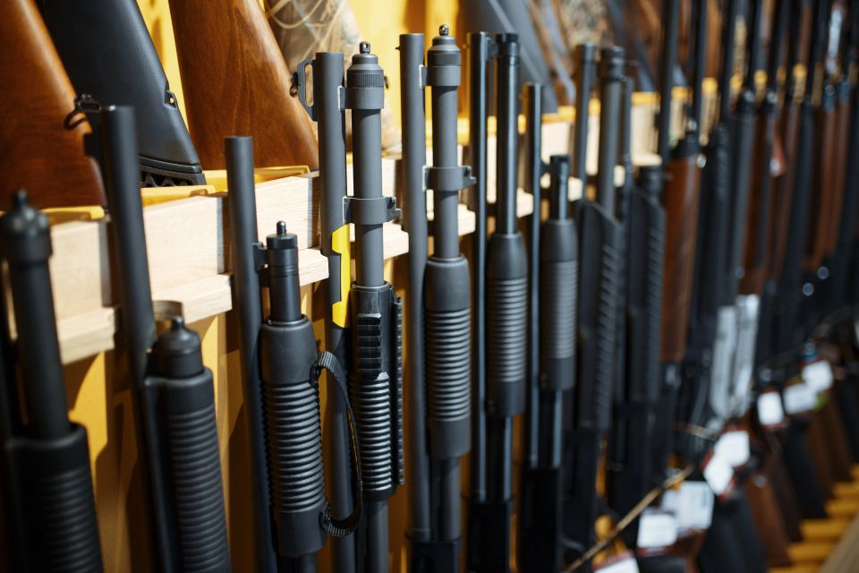 Row of pump action shotguns standing in a wooden rack at a gun shop