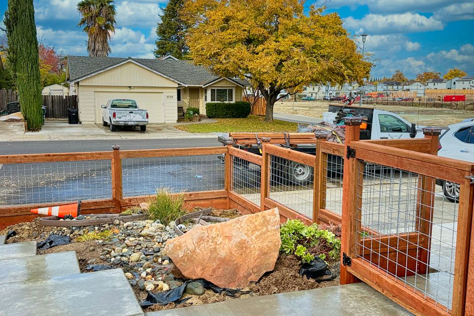 Wooden fence with wire mesh panels enclosing landscaped front yard