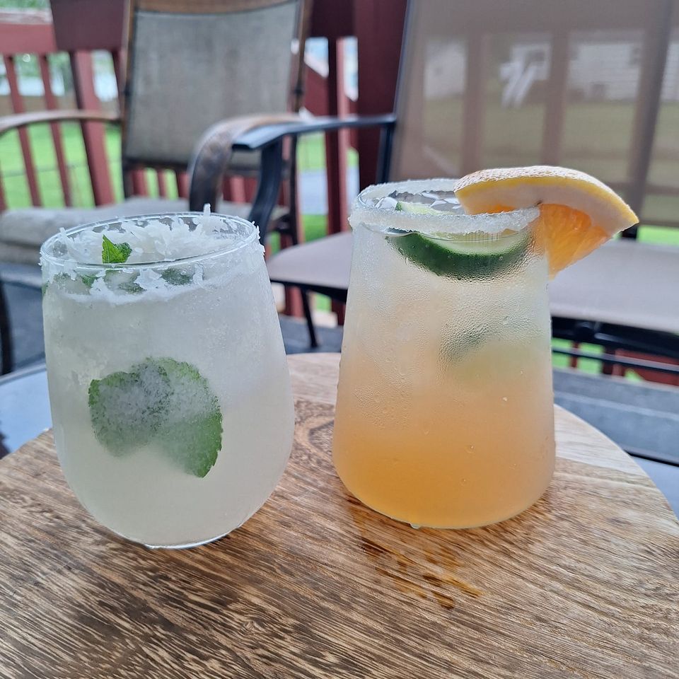 Two chilled mocktails garnished with lime and citrus slices, served on a wooden table