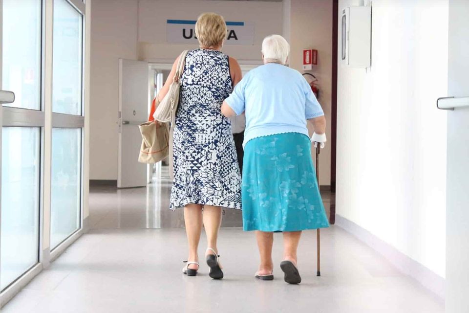senior with cane walking in facility with assistance