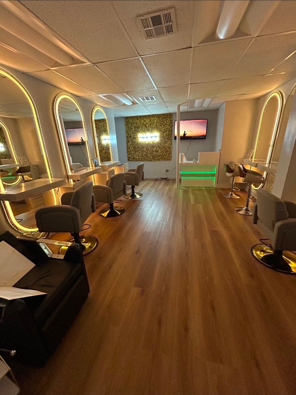 Wide view of hair braiding stations with backlit mirrors and reception desk inside the Los Angeles salon