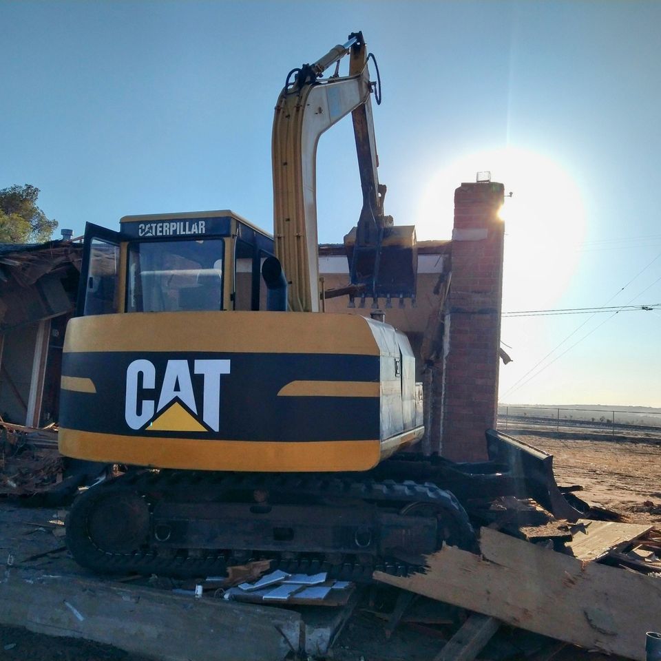 Image of Steel Track Back Hoe, Cat Brand, At the end of a long work day with the sun setting.