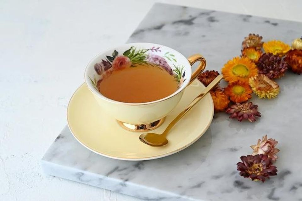 Cup of tea with fine china and dried flowers strewn about
