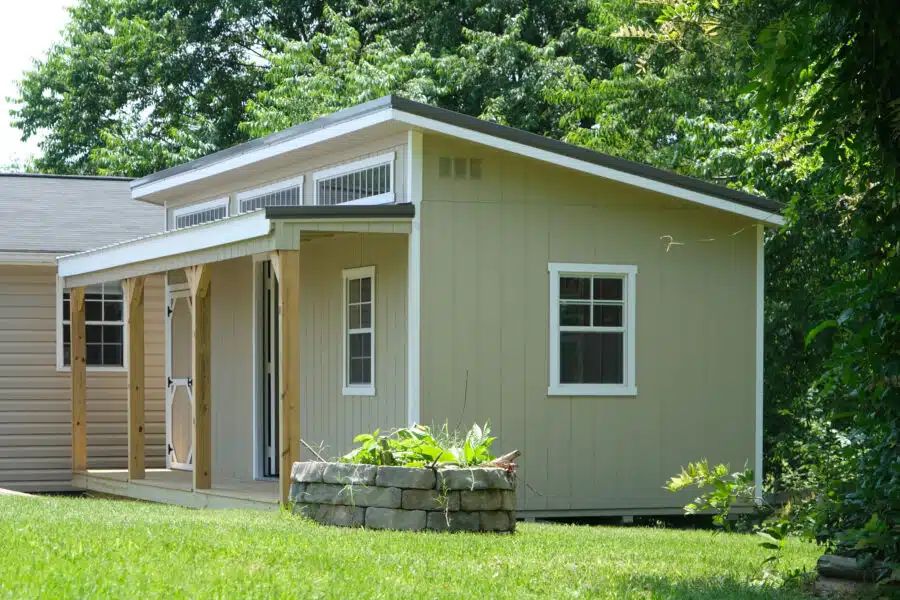 Sage green studio shed with covered porch and clerestory windows in a Knoxville TN backyard