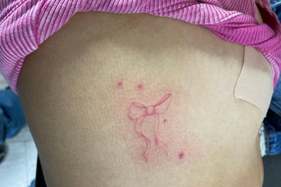 Image of a woman showing her delicate and pink tattoo on her right side