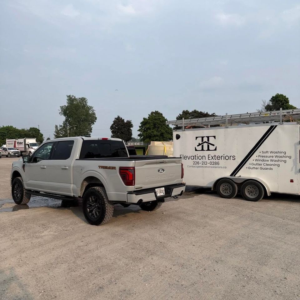 Elevation Exteriors branded exterior cleaning trailer with roof ladders beside Ford F-150 pickup truck