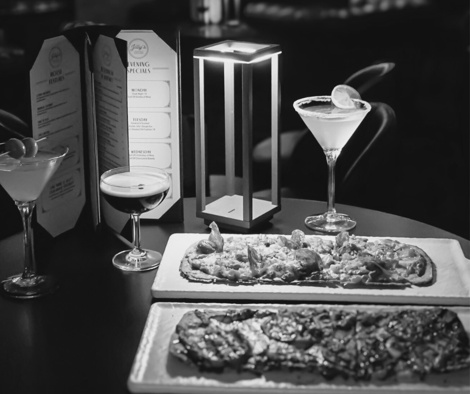 Two of Jilly's delicious appetizers with drinks on a dimly lit table.