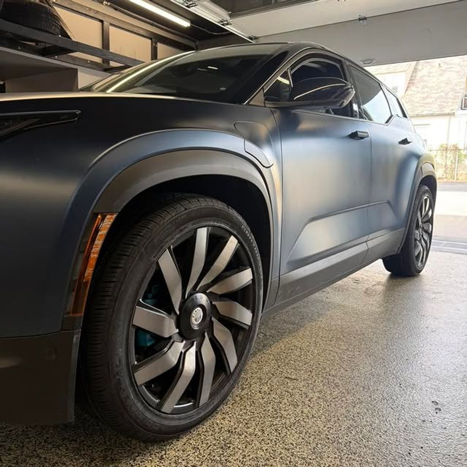 Matte gray SUV with new black alloy wheels installed inside tire shop in Claymont DE