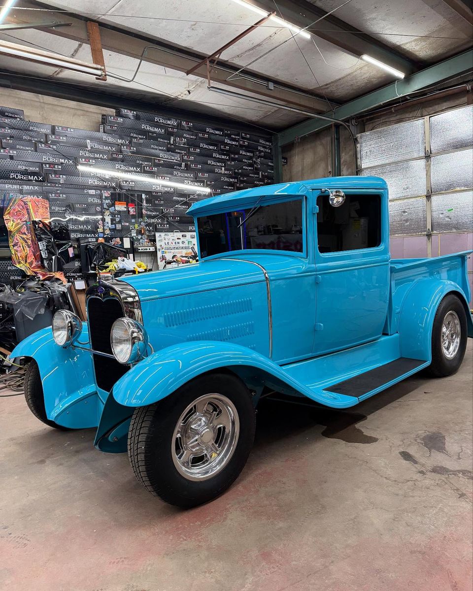 Restored light blue vintage Ford pickup truck in the window tinting shop bay
