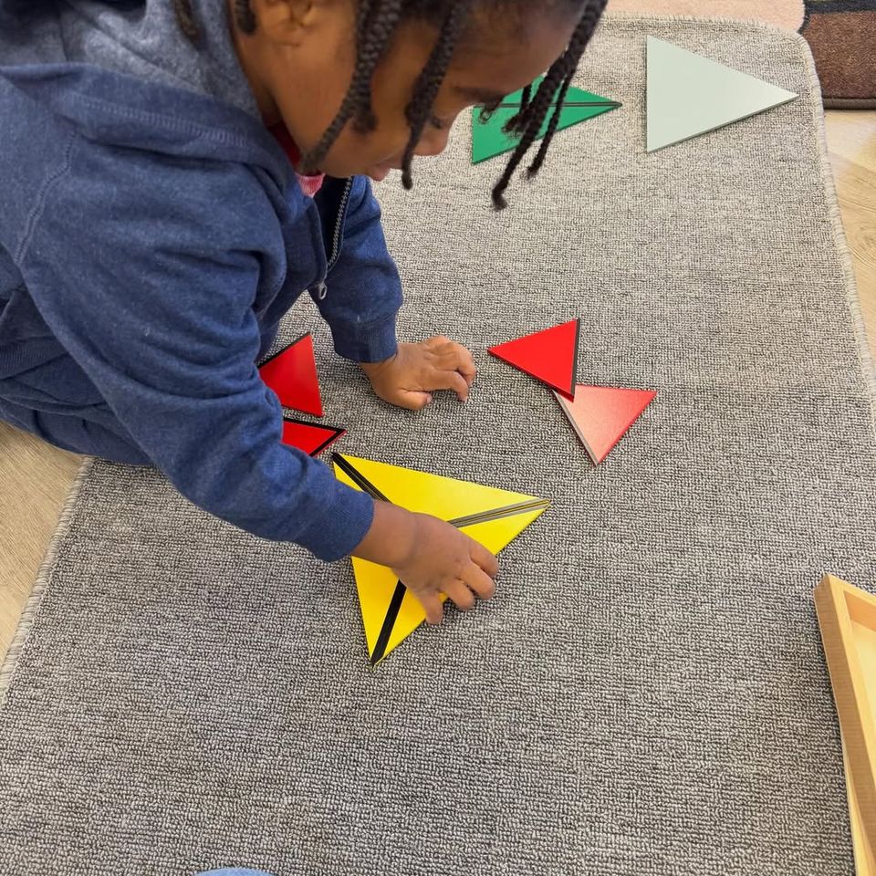 Preschooler building shapes with Montessori constructive triangles on a work rug in Palmdale CA