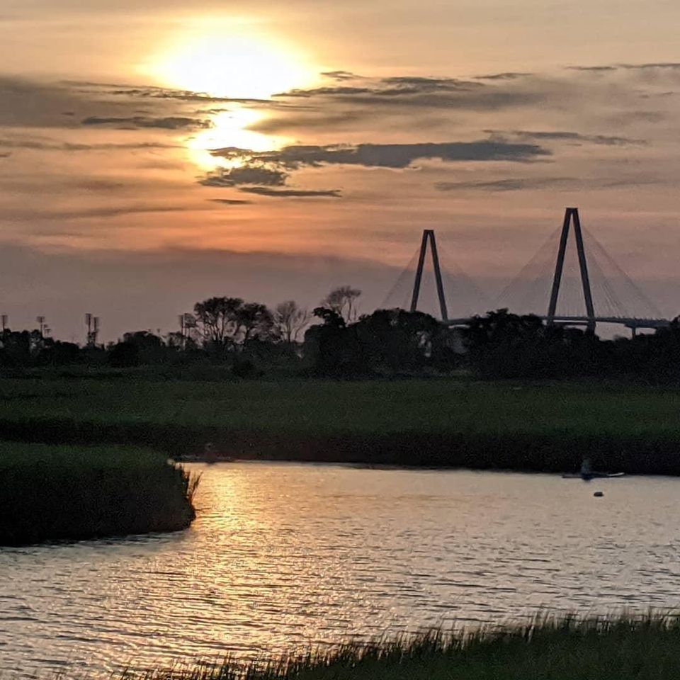 Charleston sunset over Lowcountry marsh and tidal creek with the Arthur Ravenel Jr. Bridge in the distance.