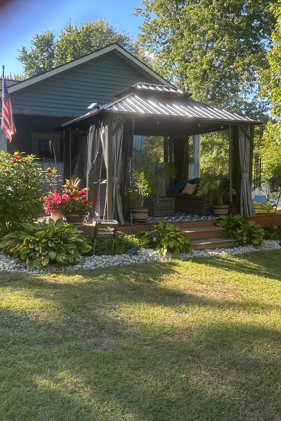 Beautiful residential landscape featuring a manicured lawn, gazebo, colorful flower beds, and well-maintained shrubs designed and maintained by R.E.P. Companies.